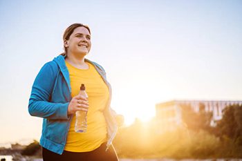 Young cute Caucasian overweight woman running in a public park.